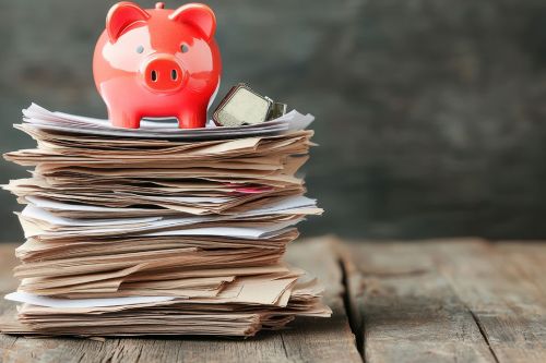 © GreenMOM - stock.adobe.com Foto: Rotes Sparschwein auf Aktenstapel